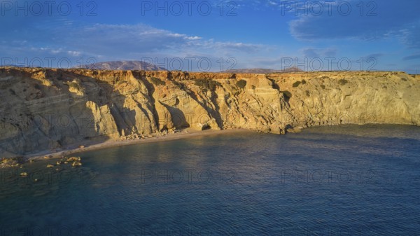 Rocky cliffs at sunset with calm water and natural beauty, drone shot, evening light, Paralia Agios