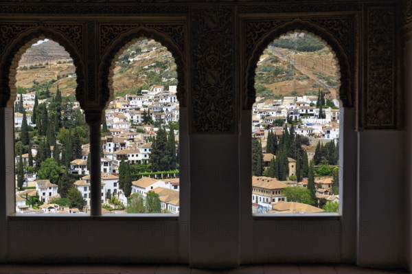 View of the city through three arabesque arched windows, Nasrid Palaces, Alhambra, Granada,