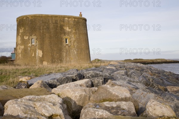 Martello tower defended from erosion by rock armour at East Lane, Bawdsey, Suffolk, England, United