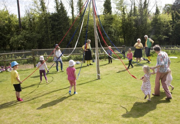Children dance around a maypole at an English country festival, Shottisham, Suffolk, England,