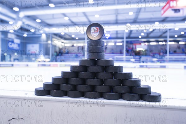 Stacked ice hockey pucks in an ice rink on the sidelines, Heilbronner Falken Vs Bietigheimer