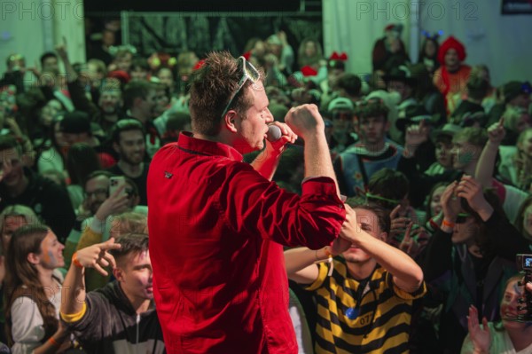 Schlager king Tobee in red shirt sings on stage in front of a rousing audience, carnival,
