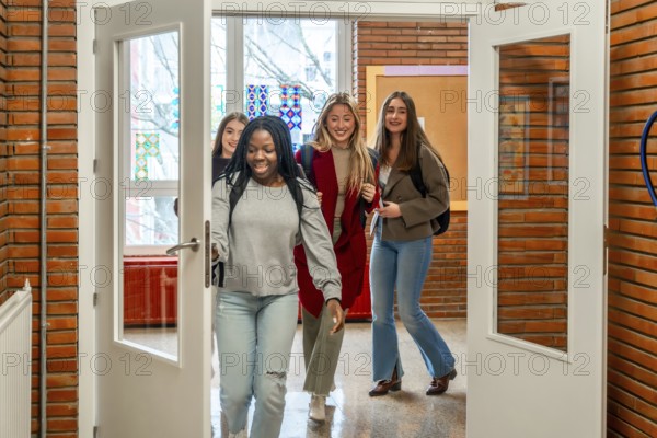 Cheerful female students are walking out of the classroom after their lesson at the university