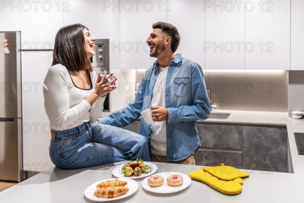 Young couple laughing and having breakfast in a modern kitchen, enjoying a moment of happiness