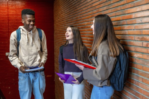 Happy diverse college students chatting and laughing together in university hallway, enjoying their
