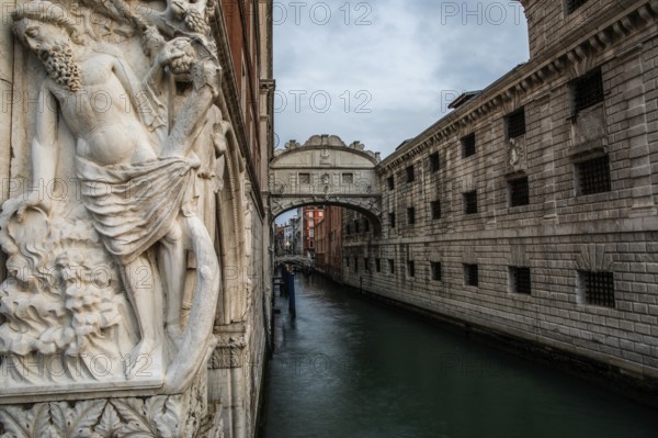 Stone sculpture of an ancient deity, Bridge of Sighs or Ponte dei Sospiri at the Doge's Palace over
