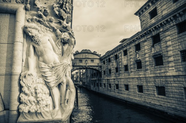 Stone sculpture of an ancient deity, Bridge of Sighs or Ponte dei Sospiri at the Doge's Palace over
