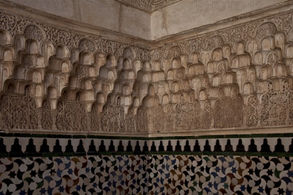 Nasrid palace, stucco wall decoration over tiled plinth in a corner of the room