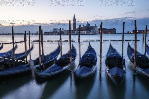 Morning light in front of sunrise, Venetian gondolas, boat dock at St Mark's Square, church of San