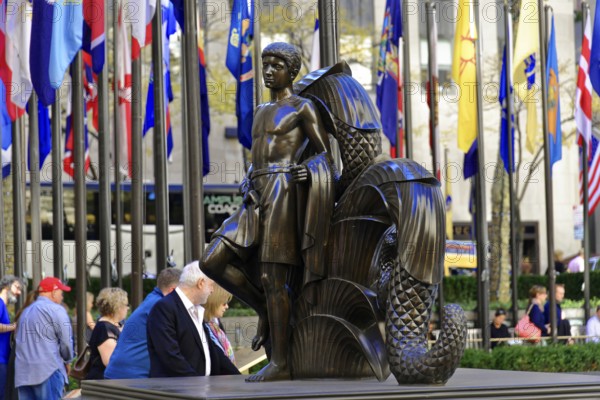 Rockefeller Center, bronze sculpture of a standing man in front of international flags, surrounded