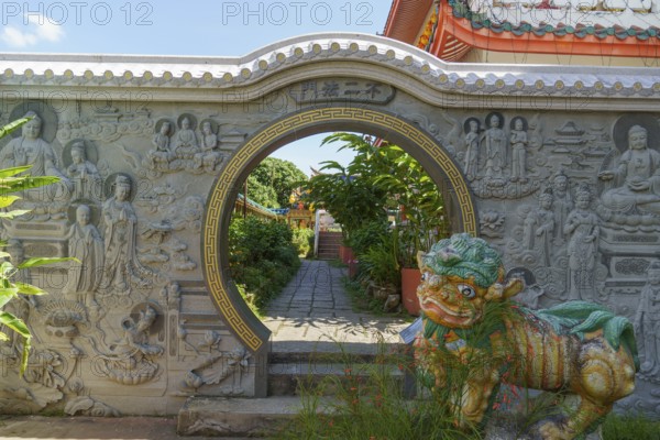 Entrance gate with stone reliefs and colourful figure. Leads to a well-kept garden path, penang,