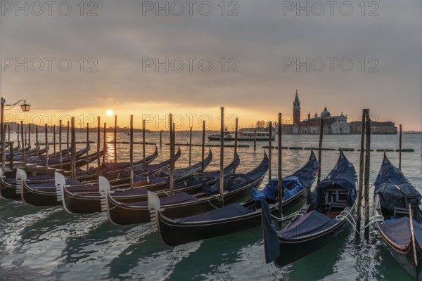 Cloudy atmosphere at sunrise, gondolas, San Giorgio Maggiore church in the background, Venice,
