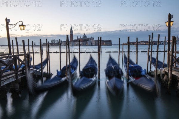 Morning light in front of sunrise, Venetian gondolas, boat dock at St Mark's Square, church of San