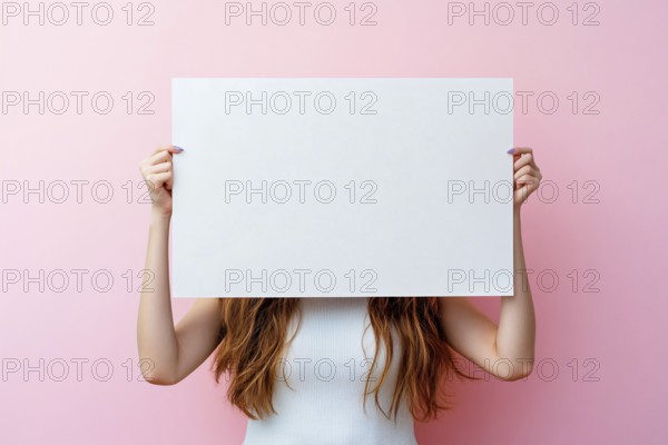 White empty sign being held by woman in front of pastel pink studio background. Generative AI, AI