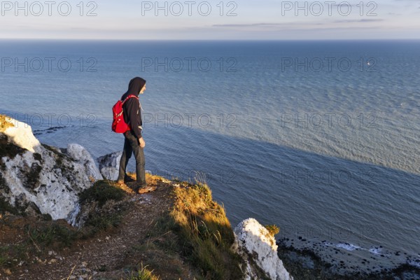 Hiker enjoying views of cliffs, chalk coast, Beachy Head, Eastbourne, South Downs, Sussex, England,