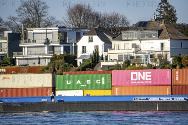 Container cargo ship on the Rhine near Düsseldorf-Bockum, villas on the banks of the Rhine, the