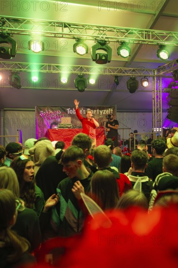Schlager king Tobee heats up the audience in a party tent illuminated with green lights, carnival,