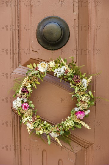 Detail of an antiquated front door with floral wreath in a building on the Krämerbrücke in the