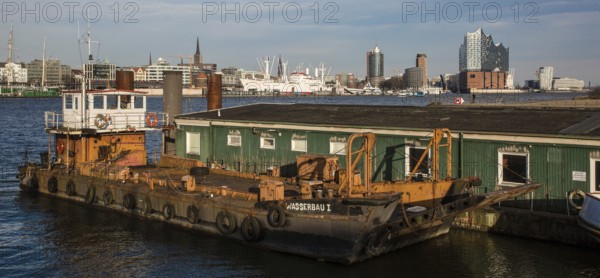 Hamburg harbour, working ship WASSERBAU I in front of wooden barracks, city skyline with museum