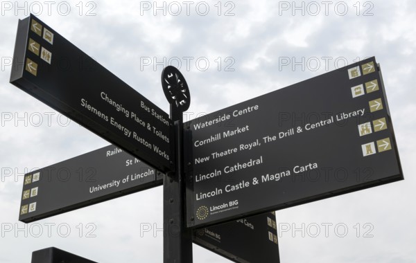 Looking up at signpost pointing to places of interest, city of Lincoln, Lincolnshire, England, UK