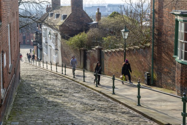 People walking up Steep Hill cobbled street, Lincoln, Lincolnshire, England, UK