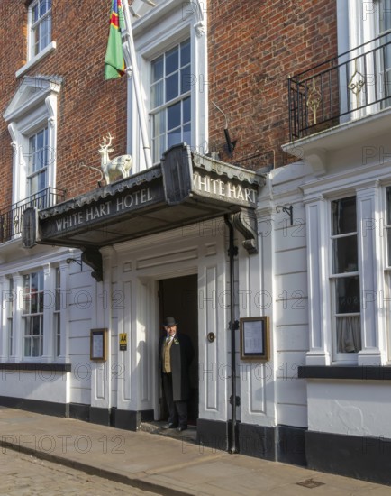 Doorman standing in entrance door of historic White Hart Hotel, Bailgate, city of Lincoln,