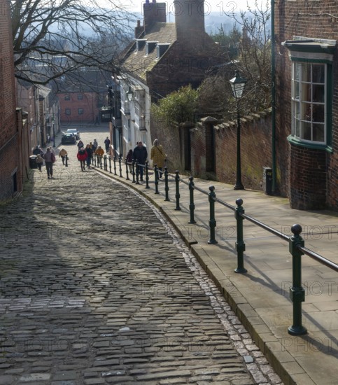 People walking up Steep Hill cobbled street, Lincoln, Lincolnshire, England, UK