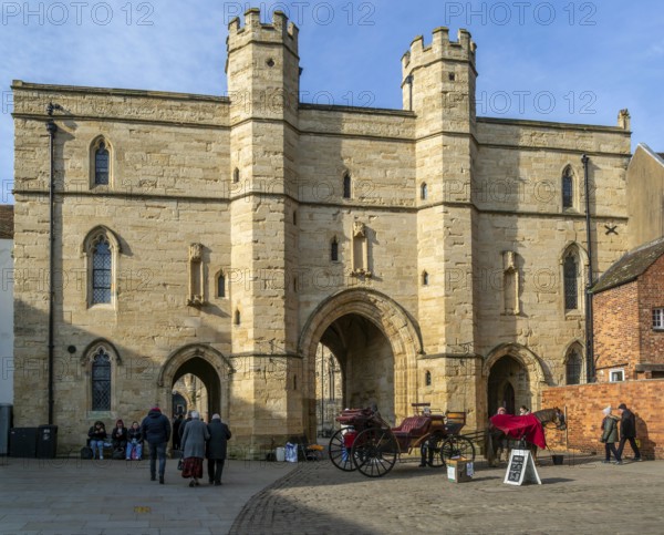 Sun shining on Exchequer Gate with horse carriage rides, Minster Yard, city of Lincoln,