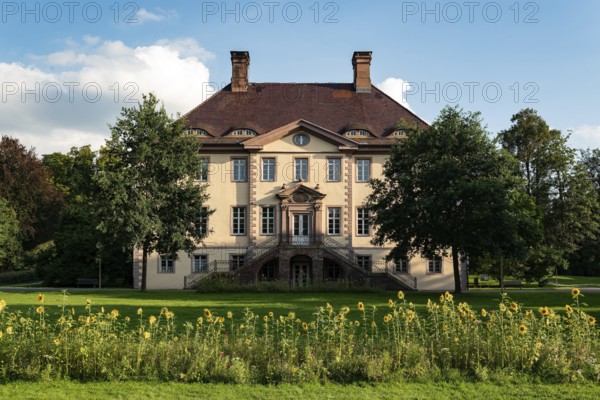 Schieder Castle presents itself under a blue sky as an elegant manor house with a flower meadow and