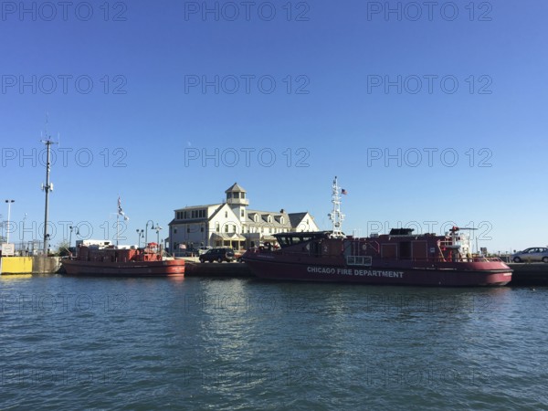 Fireboats on the banks of a river next to a historic building under a blue sky, chicago, usa
