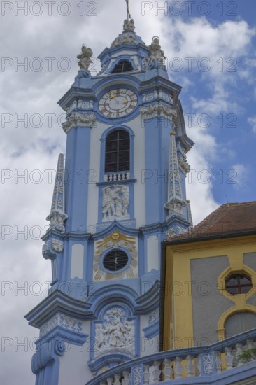 Baroque church tower with clock and richly decorated structures in blue and yellow, wachaus, donau,