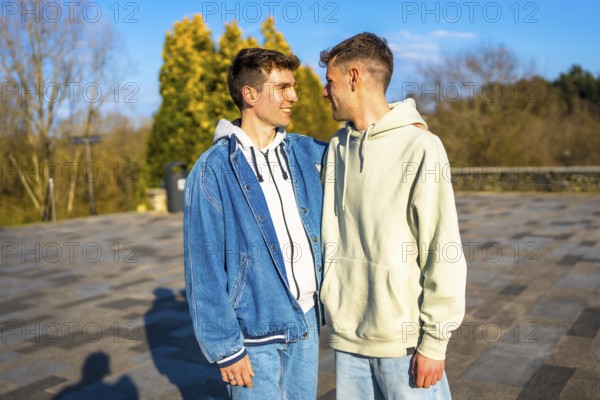 Two men embracing and smiling in a public park, sharing a joyful romantic moment together under the