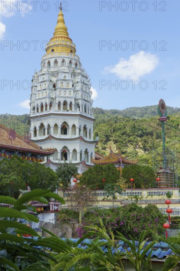 Imposing pagoda with golden spire, surrounded by green hills and blue sky, penang, malaysia