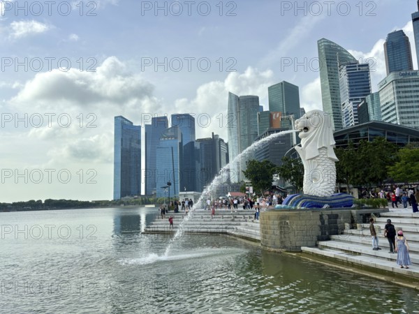 Merlion fountain spouts water in front of the impressive skyline and clouds, singapore