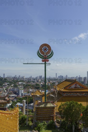 A temple with detailed roof decorations and city skyline in the background, penang, malaysia