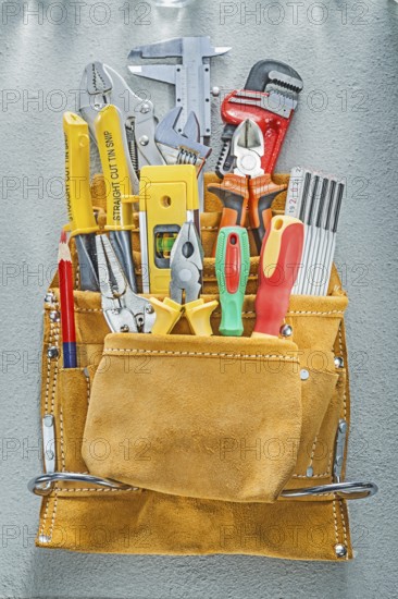 Assortment of construction tooling in tool belt on concrete background