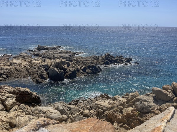 Rocky coastline with crystal clear water under a blue sky, cagliari, sardinia, italy