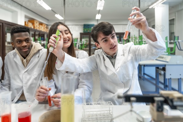 Young chemistry students wearing lab coats performing experiment using test tubes and other