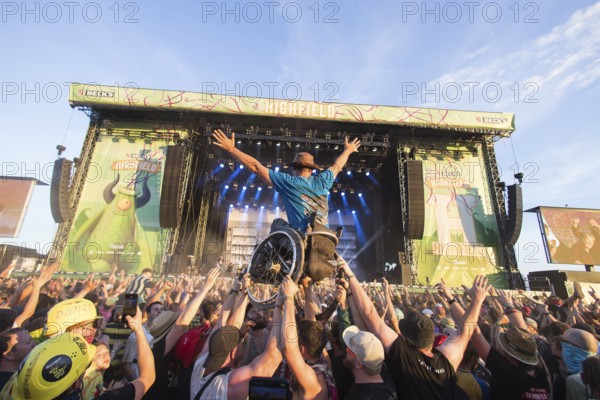 A wheelchair user is carried across the audience during the performance of the band Feine Sahne