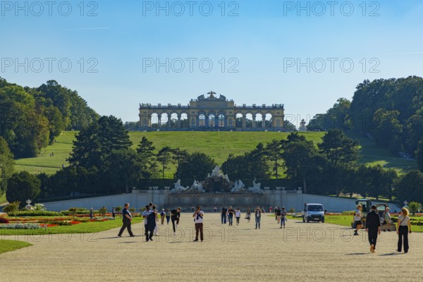 Tourists stroll in the extensive park of Schönbrunn Palace with a view of the Gloriette, Vienna,