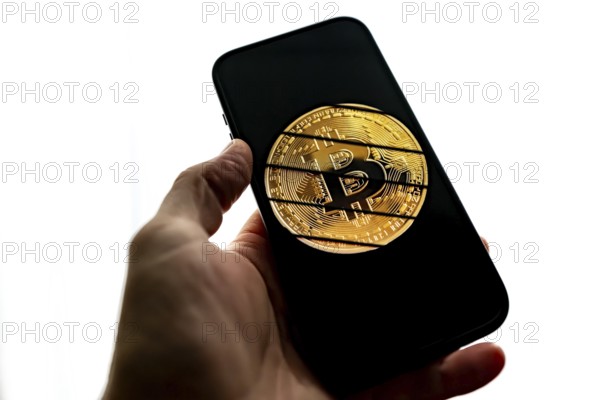 Smartphone held by hand, symbol image cryptocurrency, digital currency, golden coin Bitcoin,