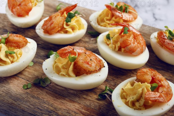 Boiled eggs stuffed with yolk and seasoned with mayonnaise, stuffed eggs with shrimp, on a wooden