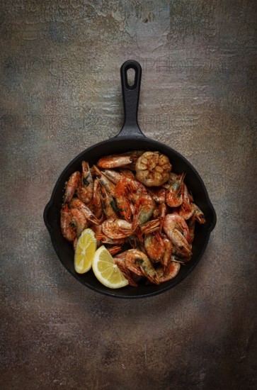Fried shrimps, in a cast-iron pan, shrimps for beer, in a newspaper, on a gray table, there are no