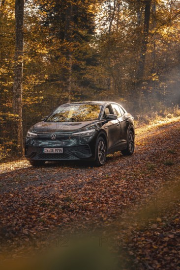 Car in an autumnal forest illuminated by sunbeams, calm atmosphere, electric car VW ID5, Gechingen,
