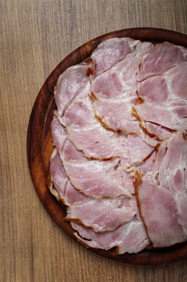 Sliced pork neck, boiled and smoked, smoked pork neck, sliced, on a wooden chopping board, close-up