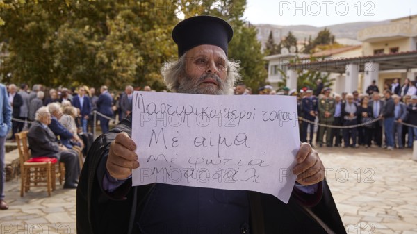 Priest shows a sign during a meeting in front of a building, Visit of the Federal President