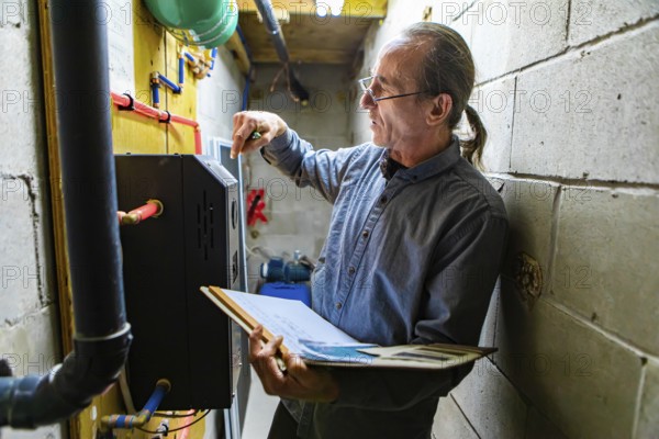 Middle aged home Inspector is visiting the equipment technical room during an inspection. Caucasian