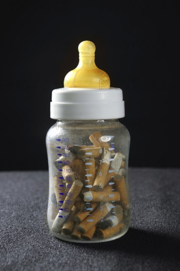 Nicotine tobacco addiction still baby bottle and used cigarettes