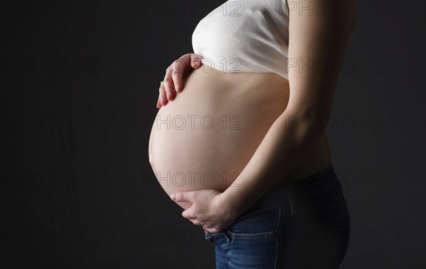 Pregnant woman, expectant mother on black background, close-up of pregnant belly, activity during