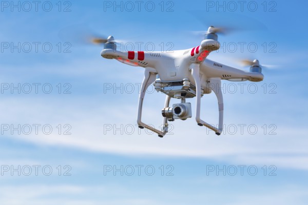 Flying quadcopter drone UAV with digital camera in blue sky, takes aerial pictures world around